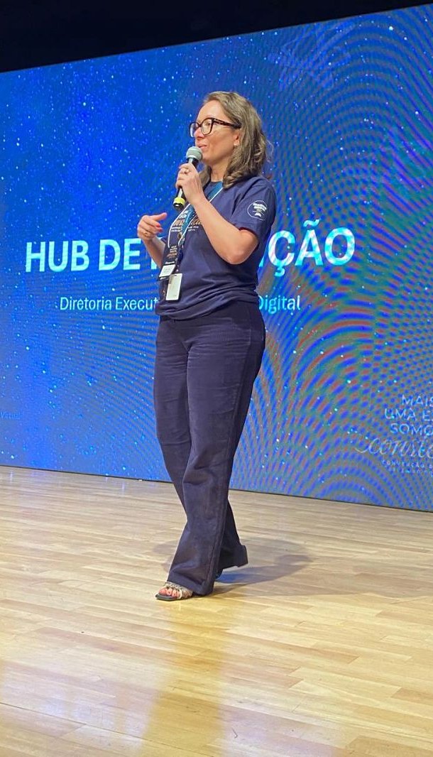 Cláudia Weiss palestrando com microfone no palco